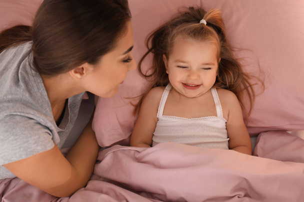 Mother putting  daughter to bed  - Valokuva, kuva