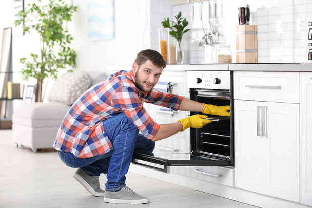man cleaning oven - Фото, изображение