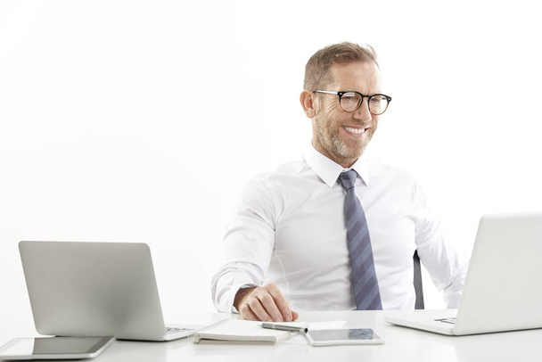 Successful middle aged businessman wearing shirt while sitting at desk and working on laptops. Isolated on white background.  - Φωτογραφία, εικόνα