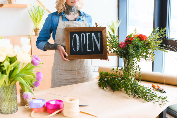 cropped shot of young florist holding open sign in flower shop - Foto, imagen