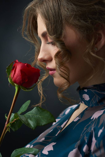 Sideview of a beatiful girl with red rose. - Valokuva, kuva