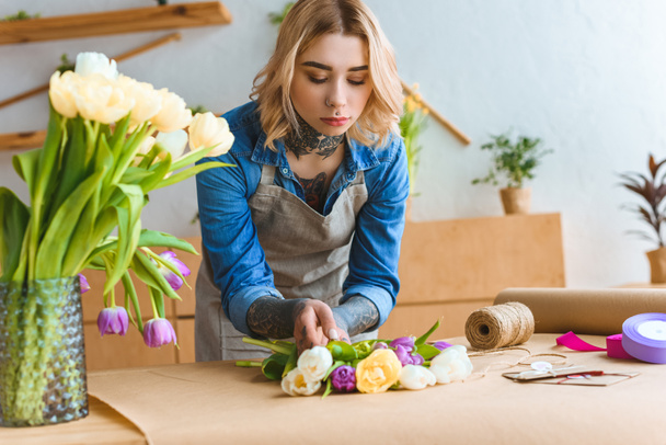 young florist working with beautiful tulip flowers at workplace - Photo, Image