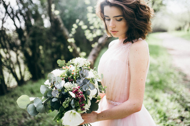 young  beautiful  bride holding flowers  outdoors - Foto, Imagen