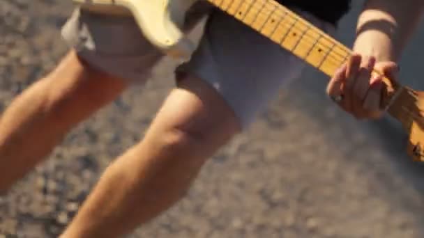 Młody człowiek skoki grając na gitarze elektrycznej - Materiał filmowy, wideo