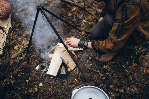 The guy fueling the fire for dinner in the woods - Fotoğraf, Görsel