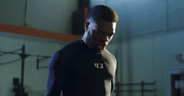 Strong black man lifting kettlebells in gym - Filmati, video