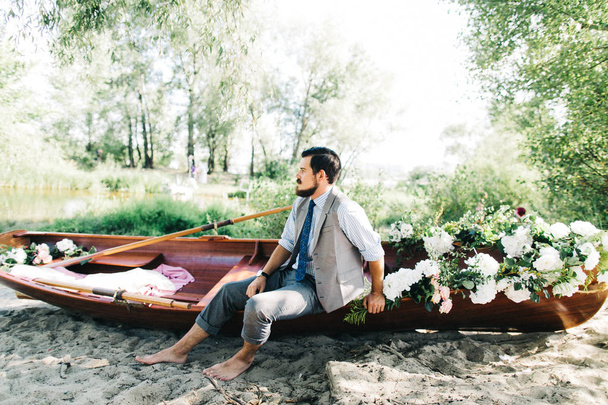 Handsome groom posing near boat outdoors   - Zdjęcie, obraz