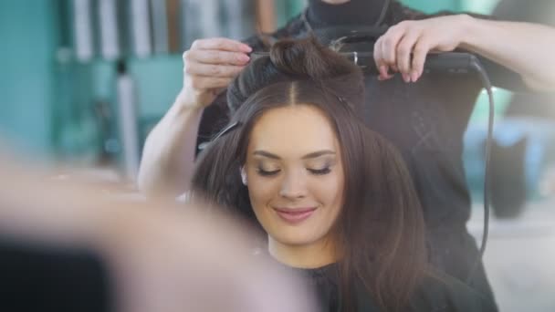 Peluquero profesional creando peinado de noche para modelo sonriente hermosa
 - Imágenes, Vídeo