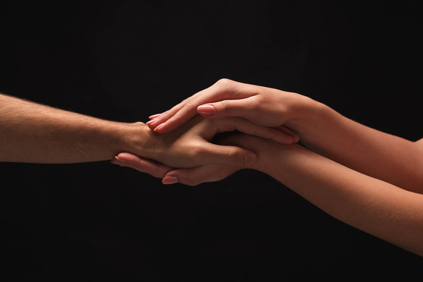 Τα χέρια του άνδρα και της γυναίκας στην αγάπη, απομονώνονται σε μαύρο - Φωτογραφία, εικόνα