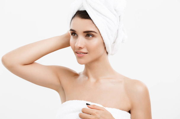 Beauty and Skin care concept - Beautiful caucasian Young Woman with bath towel on head covering her breasts, on white. - Photo, image