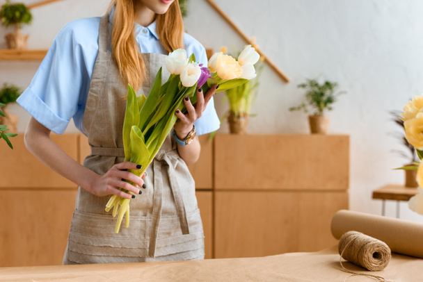 plan recadré de fleuriste dans tablier tenant de belles tulipes sur le lieu de travail
 - Photo, image