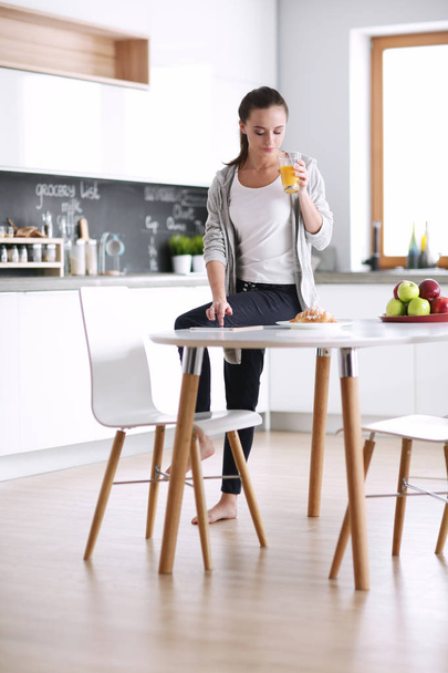 Happy woman drinking tea in the kitchen at home - Foto, Bild