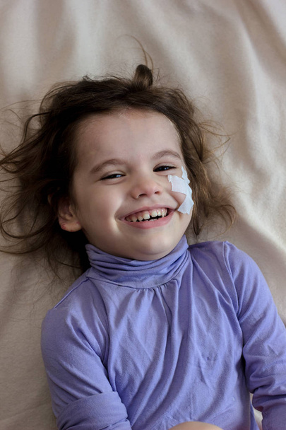 Little kid girl after accident with adhesive band on face laughing - Foto, Imagen