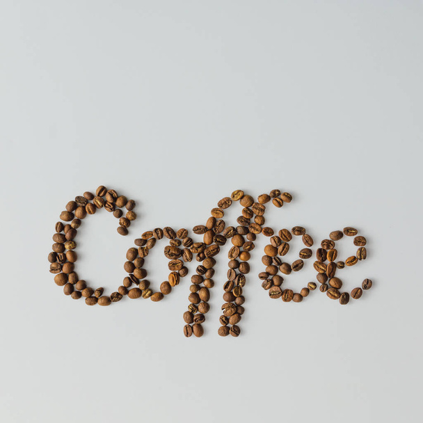 Palavra Café feito de grãos de café em fundo brilhante com espaço de cópia. Conceito de leigos planos
. - Foto, Imagem