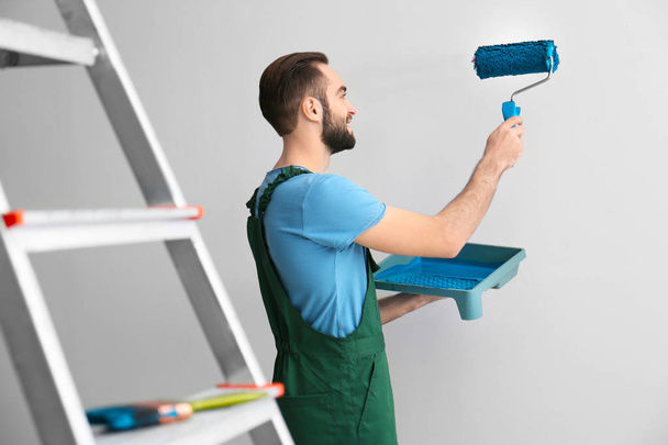 Male decorator painting wall with roller indoors - Zdjęcie, obraz