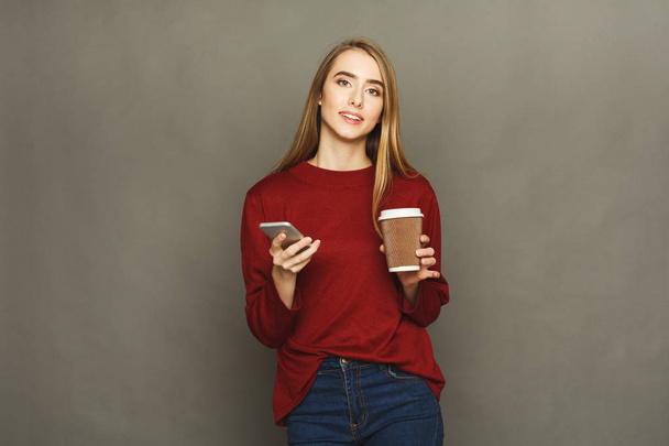 Woman holding phone and having coffee - Foto, imagen