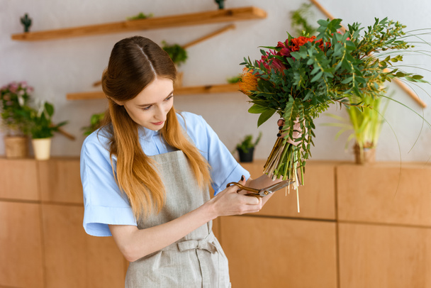 jovem florista feminina em flores de corte de avental
  - Foto, Imagem
