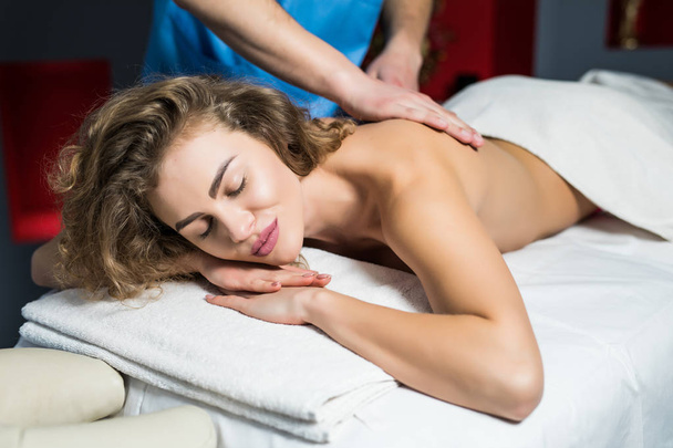 Молода жінка отримує масаж спини в спа-центрі. Жіночий пацієнт отримує лікування від професійного терапевта
. - Фото, зображення