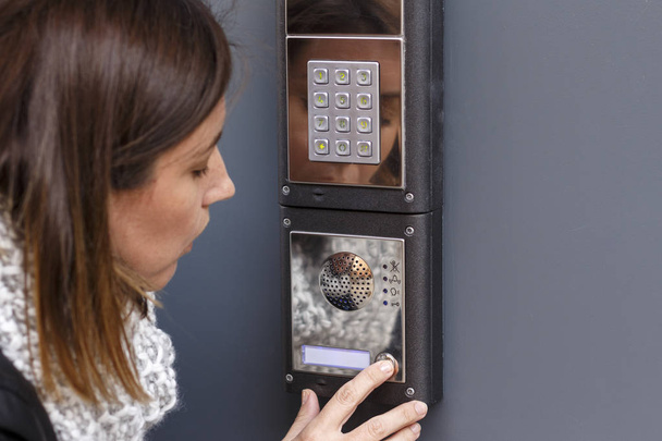 Woman pushing the button and talking on the intercom - Photo, Image