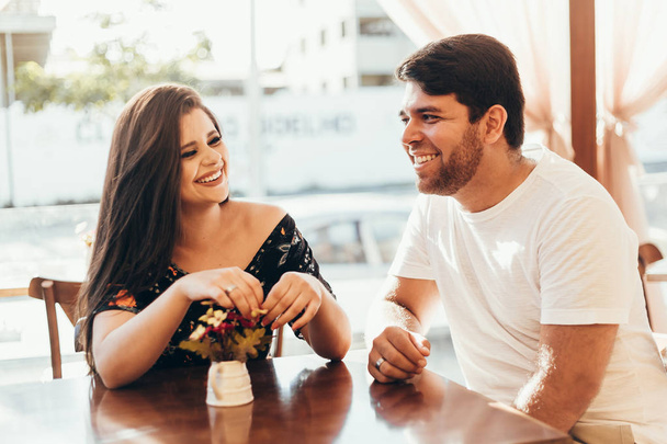Молодая пара влюбленных сидит в кафе, разговаривает и наслаждается временем, проведенным друг с другом
. - Фото, изображение
