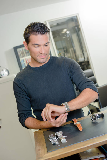 young man choosing watches in jewelry store - 写真・画像