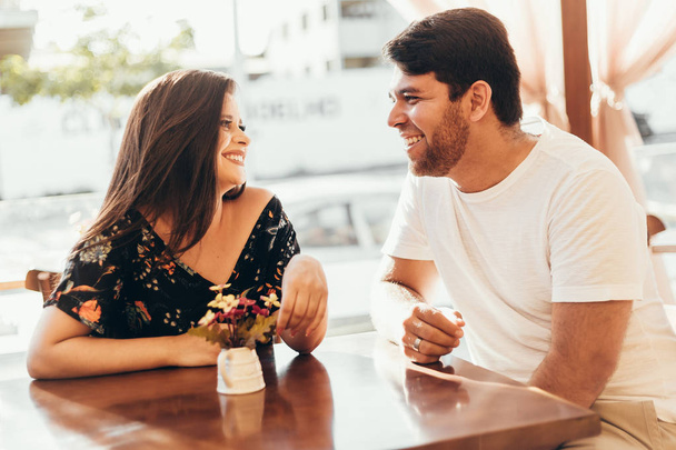 Young couple in love sitting in a cafe, having a conversation and enjoying the time spent with each other. - Foto, imagen