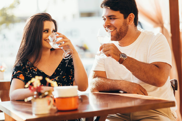 Pareja joven enamorada sentada en un café, bebiendo agua, conversando y disfrutando del tiempo que pasan juntos
. - Foto, imagen