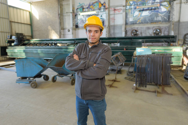 trabalhador em roupas de trabalho com capacete amarelo na fábrica
 - Foto, Imagem