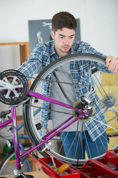 handyman fixing bike wheel in his garage - Photo, Image