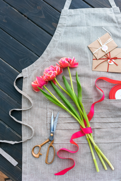 beautiful tulip flowers with envelopes, ribbon and scissors on apron - Zdjęcie, obraz