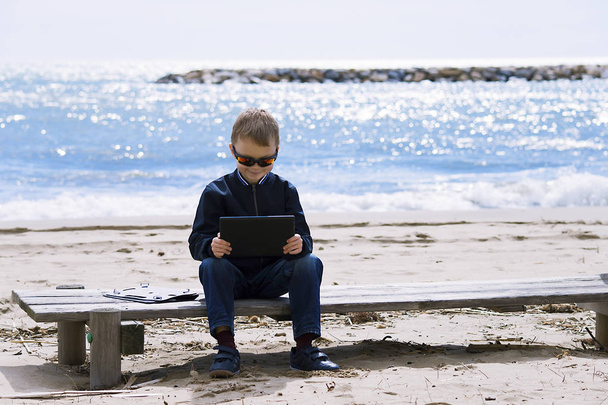 boy playing in the tablet on the seashore in the spring - Fotoğraf, Görsel