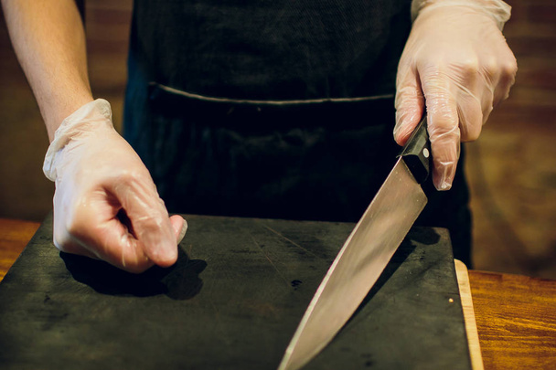 Male chef hands with knife. Cropped image of chef holding knife on empty cutting board. Cook going prepare food. - Fotoğraf, Görsel