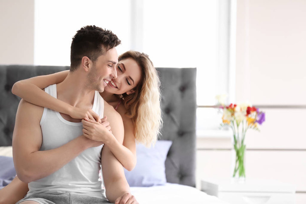 Happy young couple hugging on bed at home - Foto, immagini