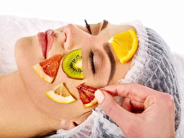 Μάσκα προσώπου από φρέσκα φρούτα για γυναίκα. Αισθητικός ισχύουν φέτες. - Φωτογραφία, εικόνα