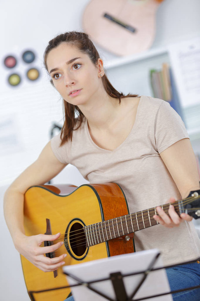 young woman holding guitar and learning to play song - 写真・画像