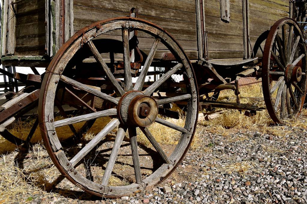 Hub, rim, and spokes of old wheels supporting a weathered wood wagon - Photo, Image