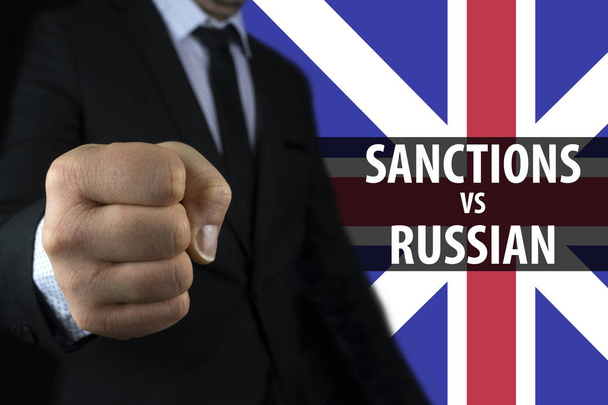 Liikemies osoittaa nyrkki taustaa vasten Englannin lipun ja kirjoitus pakotteita Venäjää vastaan
 - Valokuva, kuva