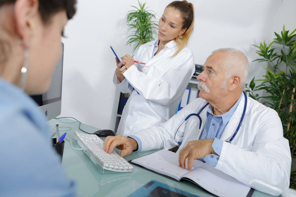 doctor using computer while in consultation with female patient - Foto, Bild
