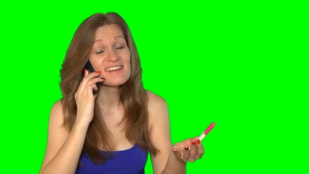 Kaunis nuori nainen puhuu matkapuhelimella ja hymyilee raskaustestissä
 - Materiaali, video