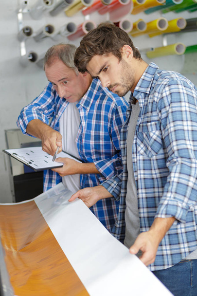workers with a large printer format inkjet working - Foto, Imagen