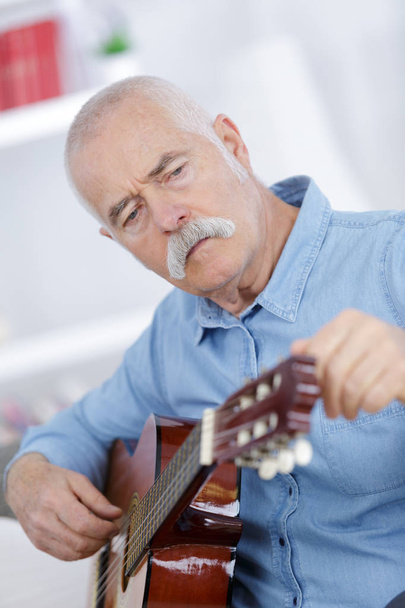 senior man at home learning to play guitar - Foto, afbeelding
