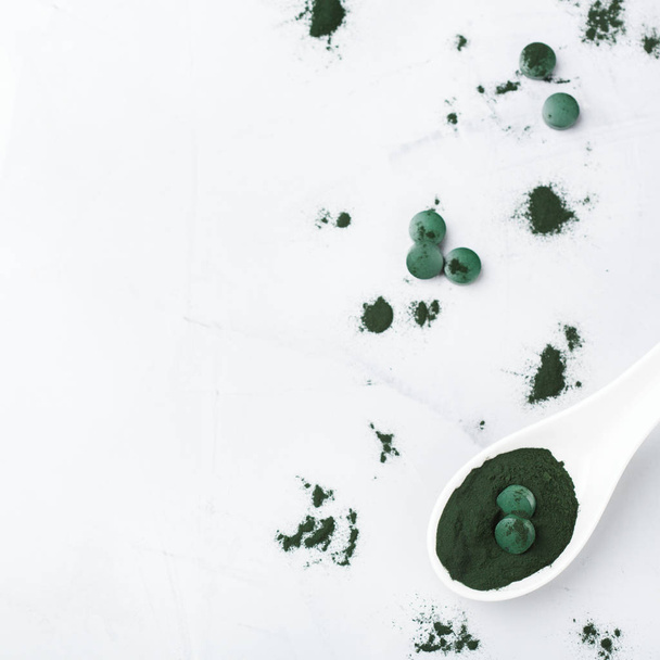 食事と栄養、superfood ビーガン有機健康的なライフ スタイルのコンセプト。地面スピルリナ藻類の粉末と錠剤またはテーブルに。宇宙トップ ビューの背景をコピーします。 - 写真・画像