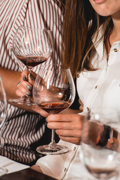 γυναίκα κρατά ποτήρι κρασί. άνθρωποι θεωρούν το χρώμα του κρασιού και δοκιμάστε πώς μυρίζει σε διαφορετικά ποτήρια - Φωτογραφία, εικόνα