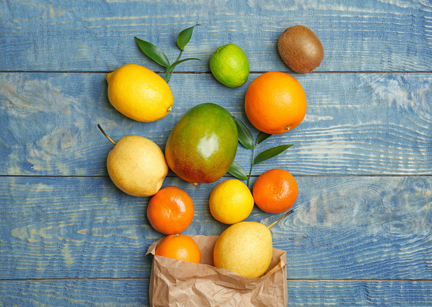 Paper bag and fresh tropical fruits on wooden background - Valokuva, kuva