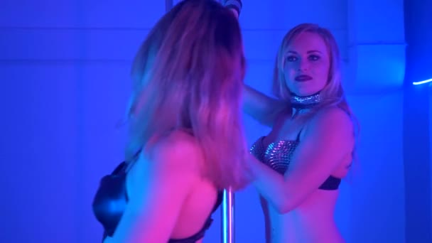 Дві молоді сексуальні стрункі жінки полюс танцює з пілоном в темному інтер'єрі
 - Кадри, відео