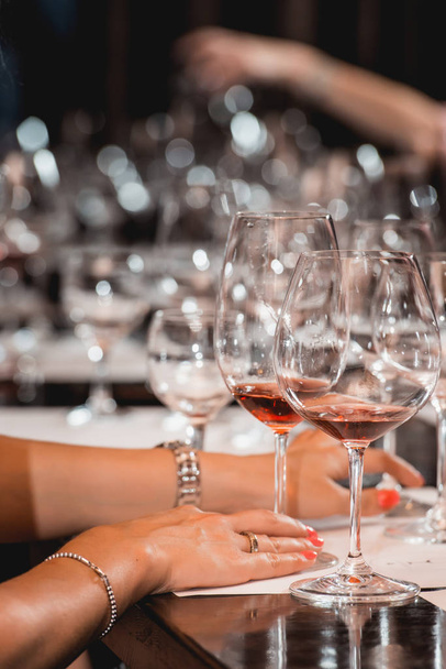 жінка тримає стакан червоного вина. люди розглядають колір вина і намагаються, як він пахне в різних келихах
 - Фото, зображення
