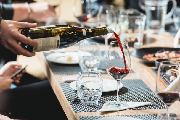 ソムリエのワインの試飲グラスに赤ワインを注ぐ - 写真・画像