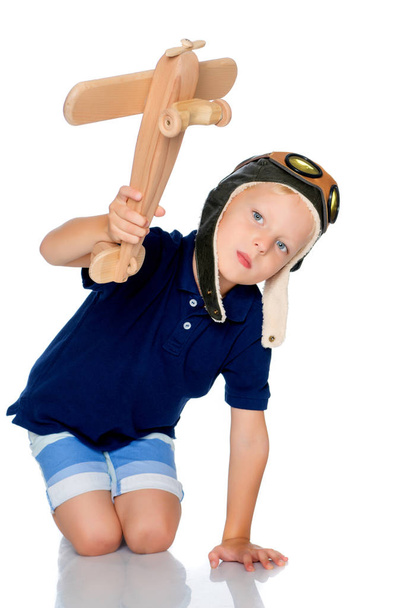 Jongetje met een houten vliegtuig. - Foto, afbeelding