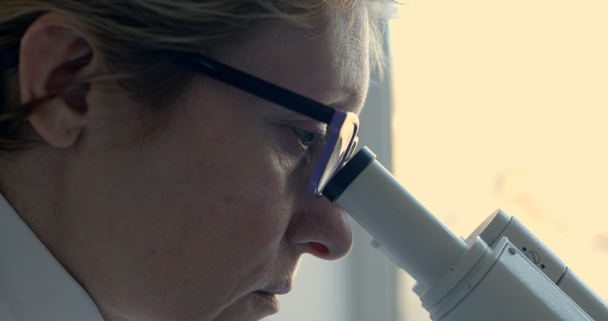 Female scientist looking through microscope - Felvétel, videó