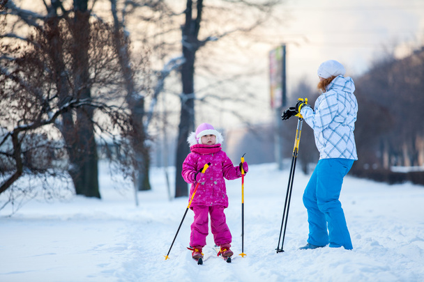 Mother and little child on ski in city park - 写真・画像